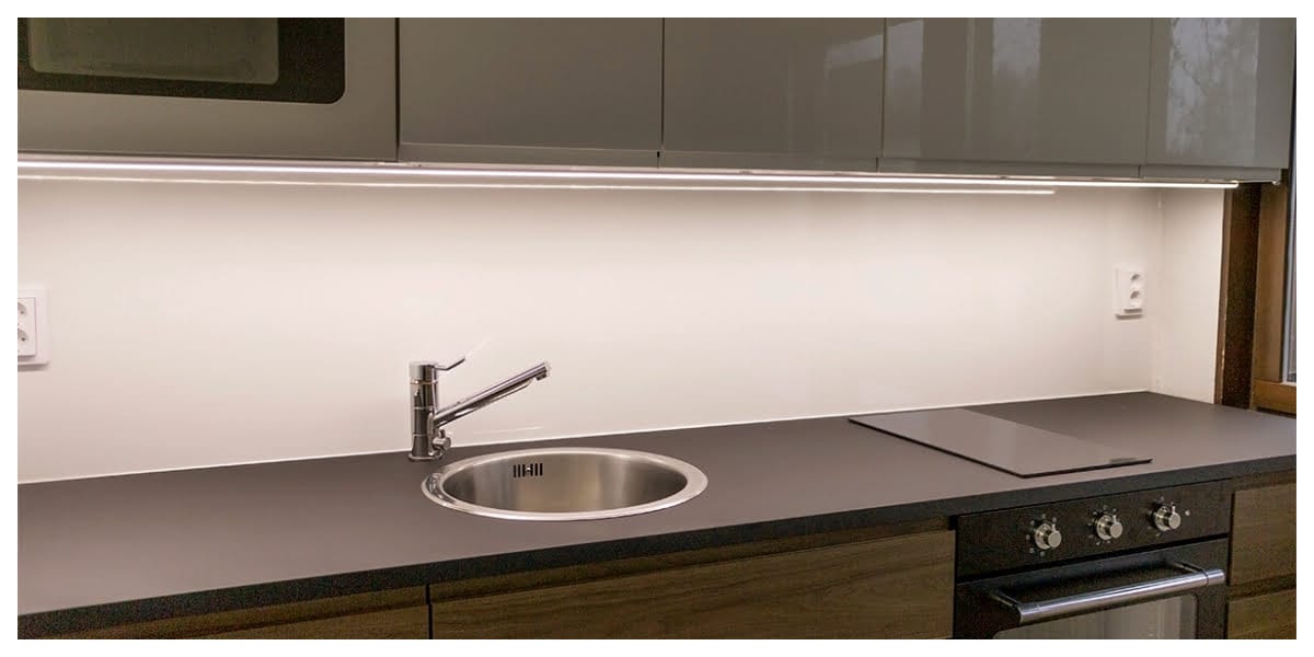 Kansikuva blogiin - LedStore Moderni keittiö, jossa LED-kaappivalaistus, tyylikäs tumma työtaso, ruostumattomasta teräksestä valmistettu pesuallas, yksikahvainen hana, valaiseva liesitaso ja kiiltävät kaapit.