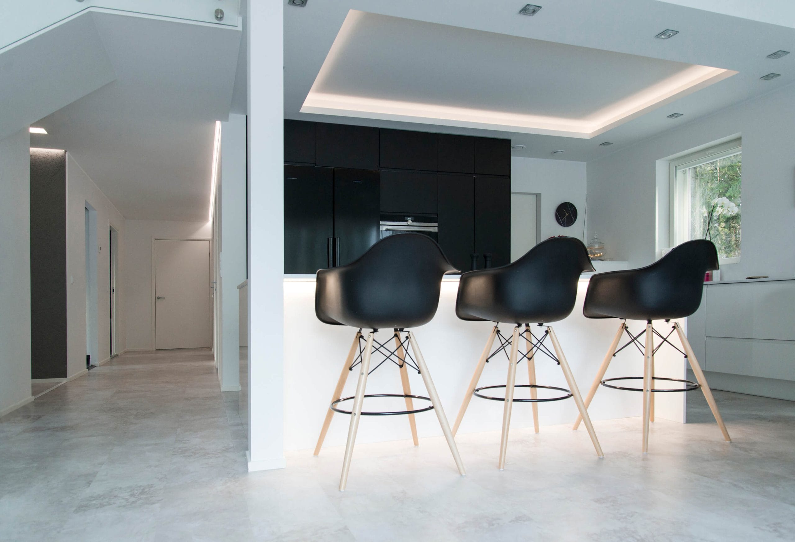 Kansikuva profiiliblogi - LedStore Moderni keittiö, jossa mustat baarituolit valkoisella saarella, tummat kaapit, upotettu katto LED-valaistuksella, ikkuna ja minimalistinen eteinen luovat tyylikkään ilmeen.